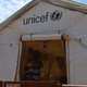 A mother and her child stand inside a UNICEF childcare tent at Sorwathe Tea Factory in Rwanda.